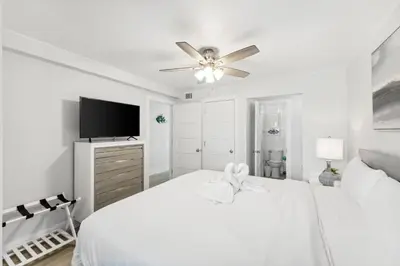 a white bedroom with a bed and a ceiling fan at The Summit 602 in Panama City Beach