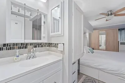 a white bathroom with a sink and a bed at The Summit 624 in Panama City Beach