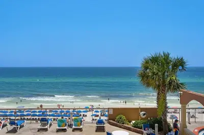 a beach with chairs and a palm tree and the ocean at 8th Floor Gulf View Beachfront Condominium by Brightwild in Panama City Beach