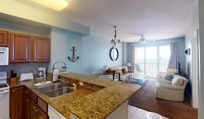 a kitchen with a sink and a living room at 8th Floor Gulf View Beachfront Condominium by Brightwild in Panama City Beach