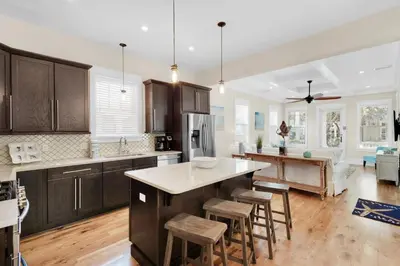 a kitchen with wooden cabinets and a island with bar stools at Calm Breeze Cottage in Santa Rosa Beach