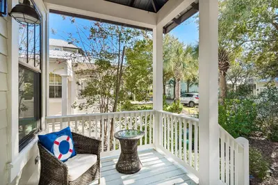 a porch with a wicker chair and a table at Calm Breeze Cottage in Santa Rosa Beach