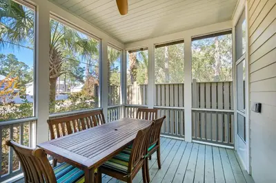 a screened porch with a wooden table and two benches at Calm Breeze Cottage in Santa Rosa Beach