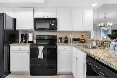 a kitchen with white cabinets and black appliances at Commodore 903 (2/2) in Panama City Beach