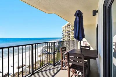 a balcony with a table and an umbrella and the beach at Commodore 903 (2/2) in Panama City Beach