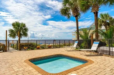 a swimming pool with two chairs and palm trees at Commodore 903 (2/2) in Panama City Beach