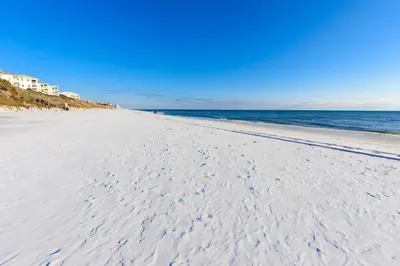 a beach with footprints in the sand and the ocean at Cassine Dream in Santa Rosa Beach