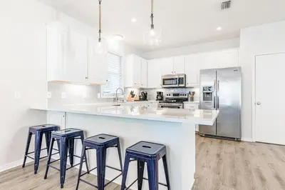 a kitchen with white cabinets and a counter with stools at Cassine Dream in Santa Rosa Beach