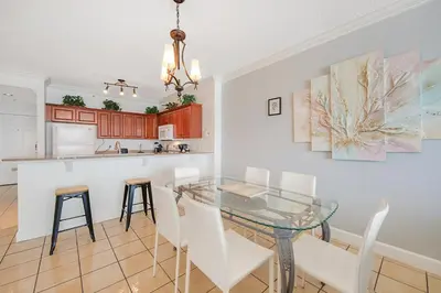 a dining room and kitchen with a glass table and chairs at Fantastic Private Complex -Beachfront 2BD Ocean Villa! Gorgeous Amenities in Panama City Beach