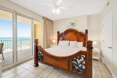 a bedroom with a bed and a balcony with the ocean at Fantastic Private Complex -Beachfront 2BD Ocean Villa! Gorgeous Amenities in Panama City Beach
