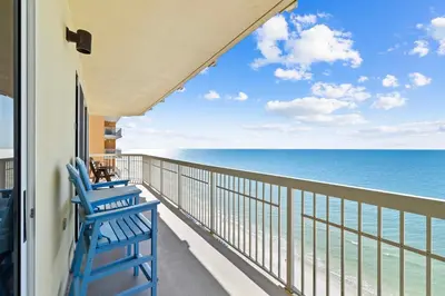 a balcony with two blue chairs looking out at the ocean at Waterfront PCB Condo with Balcony and Beach Gear! in Panama City Beach