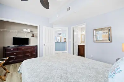a white bedroom with a bed and a television at Waterfront PCB Condo with Balcony and Beach Gear! in Panama City Beach