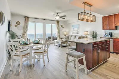 a kitchen and living room with a table and chairs at Ocean Oasis PCB Condo with Balcony and Beach Views! in Panama City Beach