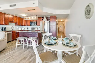 a kitchen and living room with a table and chairs at Ocean Oasis PCB Condo with Balcony and Beach Views! in Panama City Beach