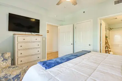 a bedroom with a large bed with a tv on the wall at Ocean Oasis PCB Condo with Balcony and Beach Views! in Panama City Beach