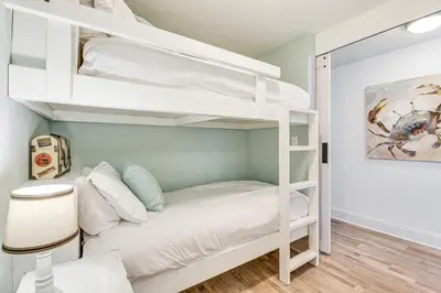 a bedroom with a bunk bed with white bunk beds at Ocean Oasis PCB Condo with Balcony and Beach Views! in Panama City Beach