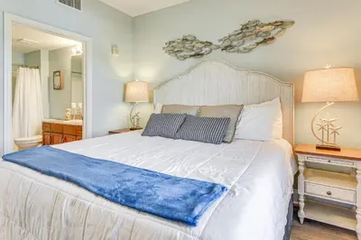 a bedroom with a bed with a blue blanket on it at Ocean Oasis PCB Condo with Balcony and Beach Views! in Panama City Beach