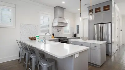 a white kitchen with a large white counter and stools at That Summer Feeling in Inlet Beach