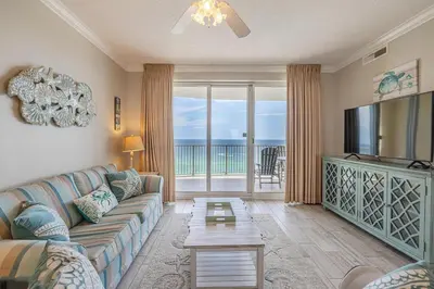 a living room with a sectional couch and a television at Ocean Villa 1102 in Panama City Beach