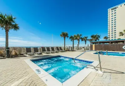 a swimming pool with palm trees and a building at Ocean Villa 1102 in Panama City Beach