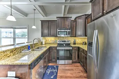 a kitchen with wooden cabinets and a stainless steel refrigerator at Half Mi to Inlet Beach Home with Grill and Fire Pit in Inlet Beach