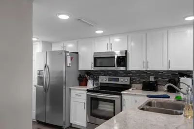 a kitchen with white cabinets and a stainless steel refrigerator at Commodore 801 (3/3) in Panama City Beach