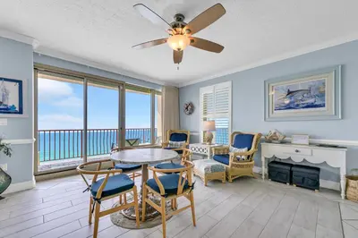 a living room with a ceiling fan and a table and chairs at Hidden Dunes 1501 in Panama City Beach