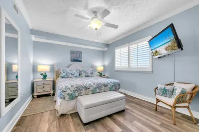 a bedroom with a bed and a tv and a chair at Hidden Dunes 1501 in Panama City Beach
