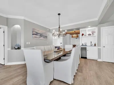 a white kitchen with a dining table and white chairs at Hidden Dunes 305 in Panama City Beach