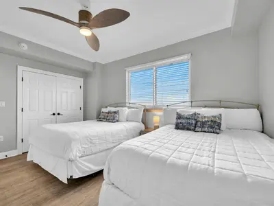 two beds in a bedroom with a ceiling fan at Hidden Dunes 305 in Panama City Beach