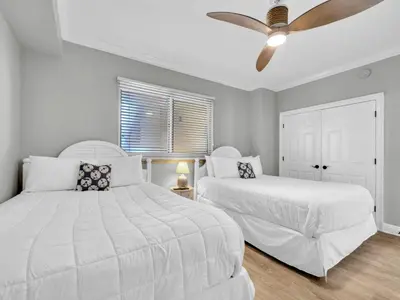 two white beds in a bedroom with a ceiling fan at Hidden Dunes 305 in Panama City Beach