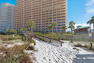 a sandy beach with a tall building in the background at Hidden Dunes 305 in Panama City Beach