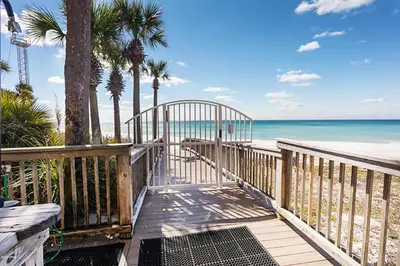a wooden walkway to the beach with palm trees and the ocean at Hidden Dunes 1704 in Panama City Beach