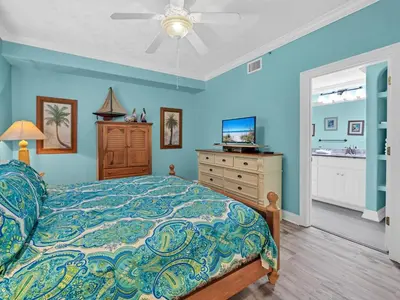 a bedroom with blue walls and a bed and a dresser at Hidden Dunes 1704 in Panama City Beach