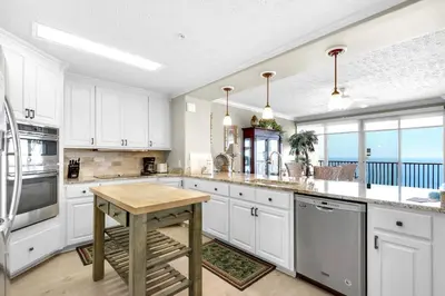 a kitchen with white cabinets and a wooden table at Hidden Dunes 1603 in Panama City Beach