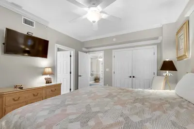 a bedroom with a large bed and a flat screen tv at Hidden Dunes 1603 in Panama City Beach