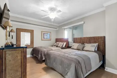 a bedroom with two beds and a dresser and a mirror at Hidden Dunes 1603 in Panama City Beach