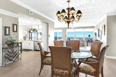 a dining room and living room with a table and chairs at Hidden Dunes 1603 in Panama City Beach