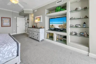 a bedroom with a bed and a tv and shelves at Hidden Dunes 1303 in Panama City Beach