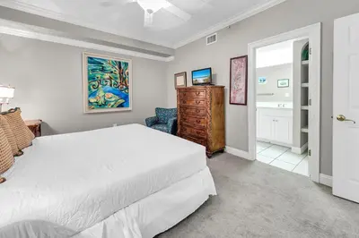 a bedroom with a white bed and a blue chair at Hidden Dunes 1303 in Panama City Beach