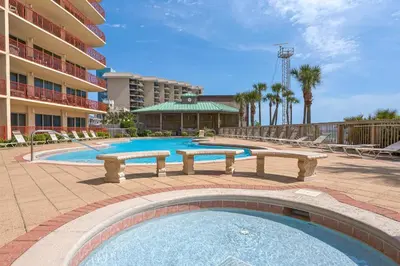 a swimming pool with benches in front of a hotel at Hidden Dunes 1703 in Panama City Beach