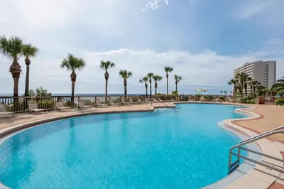 a large swimming pool with palm trees and the ocean at Hidden Dunes 1703 in Panama City Beach