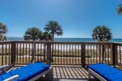 a deck with two chairs and the beach at Sunny Beach by Book That Condo in Panama City Beach