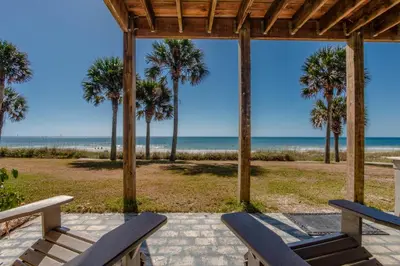 a porch with two benches and palm trees and the beach at Sunny Beach by Book That Condo in Panama City Beach