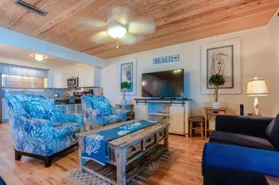 a living room with blue chairs and a table at Sunny Beach by Book That Condo in Panama City Beach