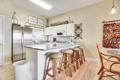 a kitchen with a counter with stools and a refrigerator at Seaside Pointe by Book That Condo in Panama City Beach