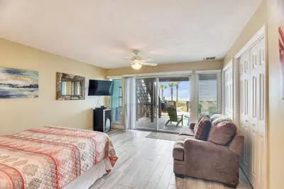 a bedroom with a bed and a couch and a balcony at Seaside Pointe by Book That Condo in Panama City Beach