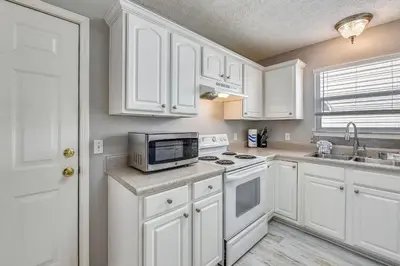 a kitchen with white cabinets and a microwave at Poolside Cabana by Book That Condo in Panama City Beach