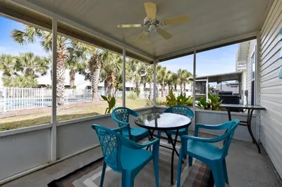 a screened porch with a table and chairs and a ceiling fan at Poolside Cabana by Book That Condo in Panama City Beach