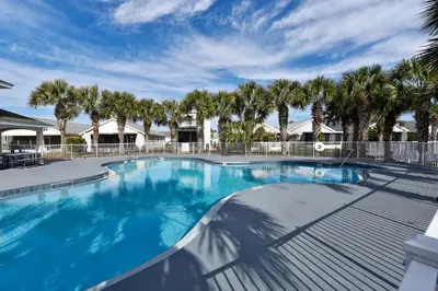 a large swimming pool with palm trees in the background at Poolside Cabana by Book That Condo in Panama City Beach
